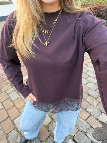 Bruine dames longsleeve met ronde hals en kanten rand aan de onderkant, gecombineerd met een lichtblauwe jeans. voor dames
